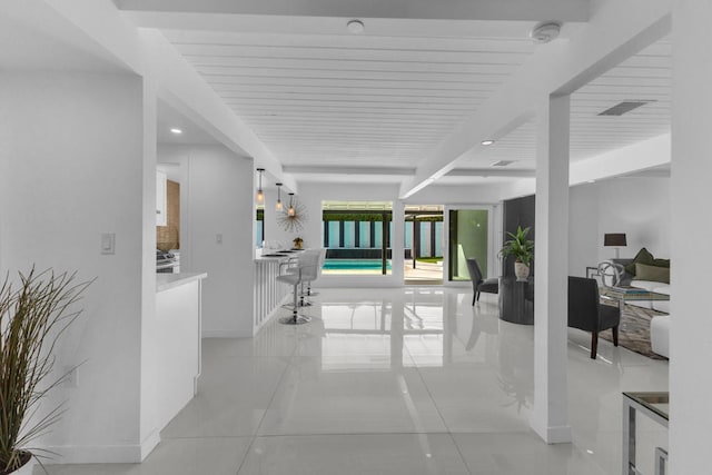 hall featuring light tile patterned flooring and beam ceiling