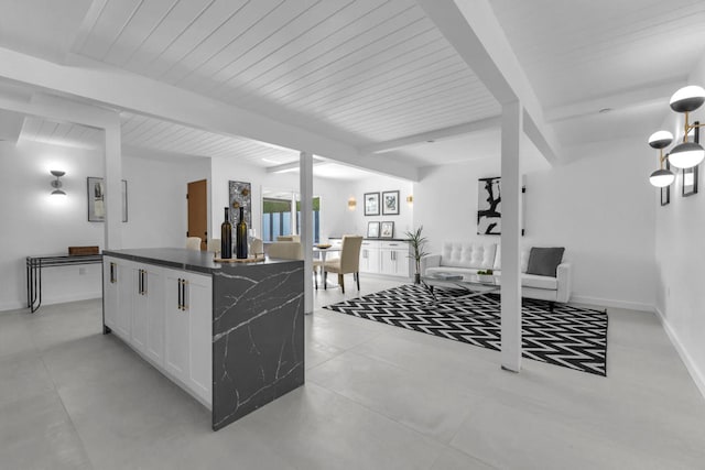 kitchen featuring beam ceiling, a kitchen island, and white cabinets