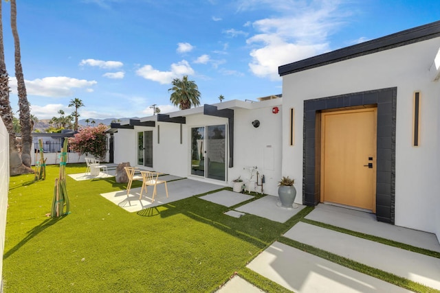 rear view of property with a patio and a lawn