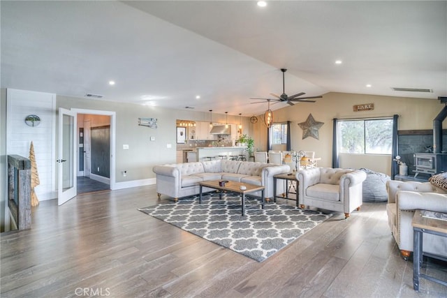 living room featuring hardwood / wood-style flooring, lofted ceiling, ceiling fan, and a wood stove