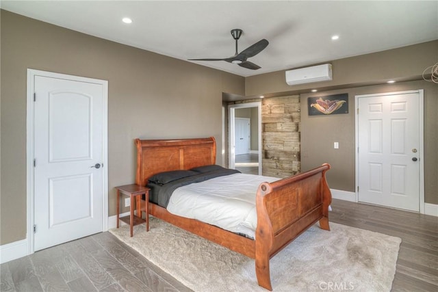 bedroom featuring a wall mounted air conditioner, hardwood / wood-style flooring, and ceiling fan