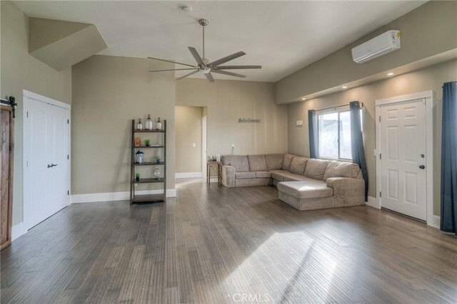 unfurnished living room with a barn door, ceiling fan, a wall mounted AC, and dark hardwood / wood-style floors