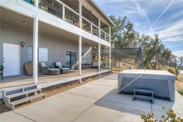 view of patio / terrace with a wooden deck, a hot tub, and a trampoline