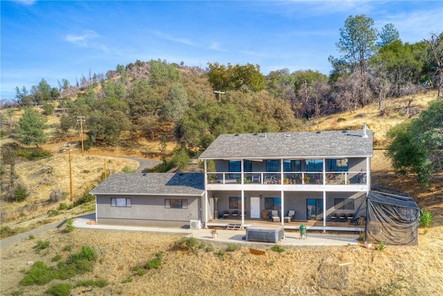 rear view of property with an outdoor living space, a balcony, and a patio