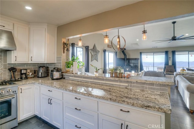 kitchen featuring high end range, kitchen peninsula, and white cabinetry