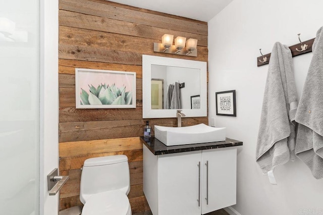 bathroom featuring wooden walls, vanity, and toilet