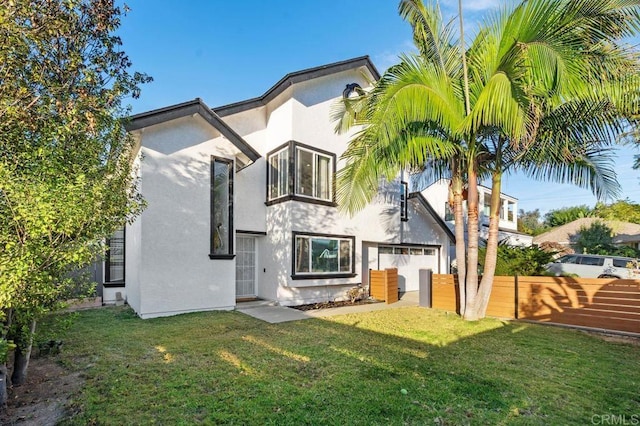 back of property with a lawn and a garage