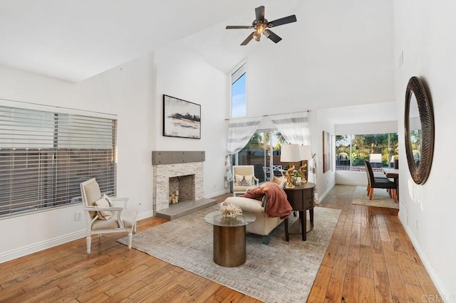 living room featuring ceiling fan, light hardwood / wood-style floors, a fireplace, and high vaulted ceiling