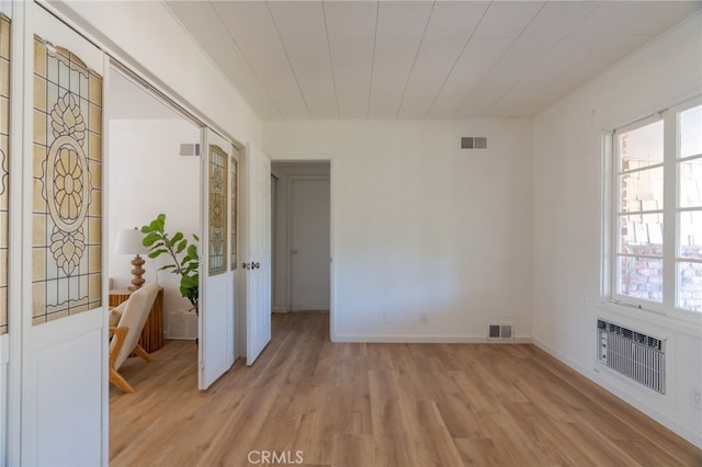 empty room featuring a wall unit AC and light wood-type flooring