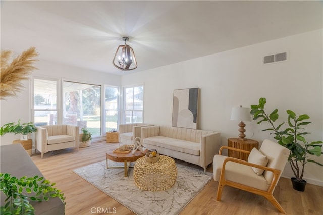 living room with light hardwood / wood-style flooring and a notable chandelier