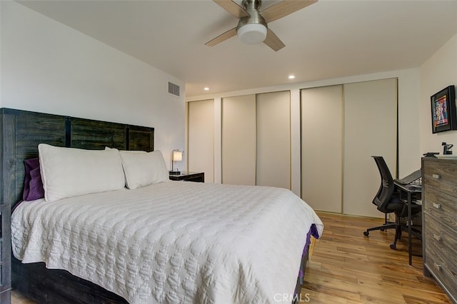 bedroom with ceiling fan, two closets, and light hardwood / wood-style floors