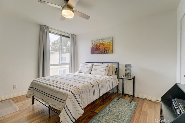 bedroom with ceiling fan, baseboards, and wood finished floors