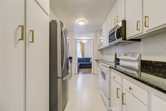 kitchen with light tile patterned floors, stainless steel appliances, white cabinetry, decorative backsplash, and dark stone counters