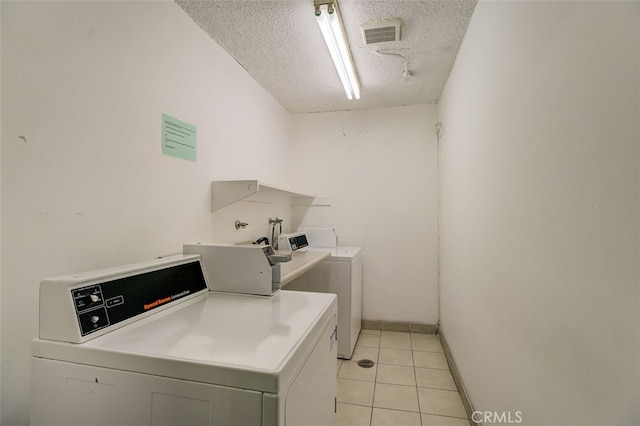 washroom with light tile patterned floors, washer and dryer, and a textured ceiling