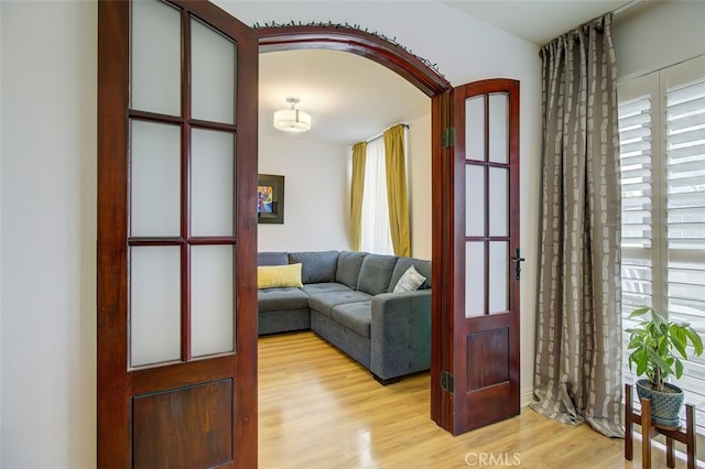 living area with light wood-style floors and arched walkways