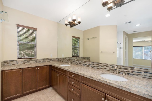 bathroom with backsplash, tile patterned floors, vanity, and an inviting chandelier