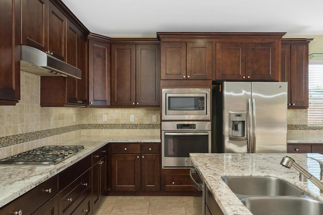 kitchen with decorative backsplash, light stone counters, sink, and stainless steel appliances