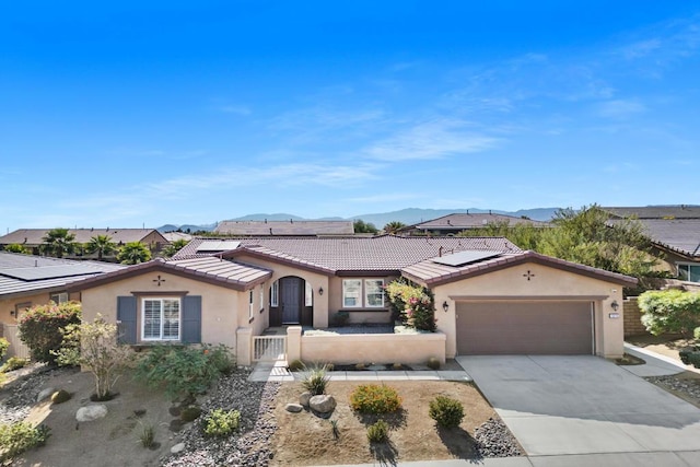 ranch-style home with a mountain view, a garage, and solar panels