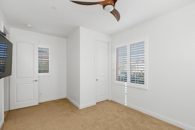 unfurnished bedroom with multiple windows, ceiling fan, a closet, and light colored carpet