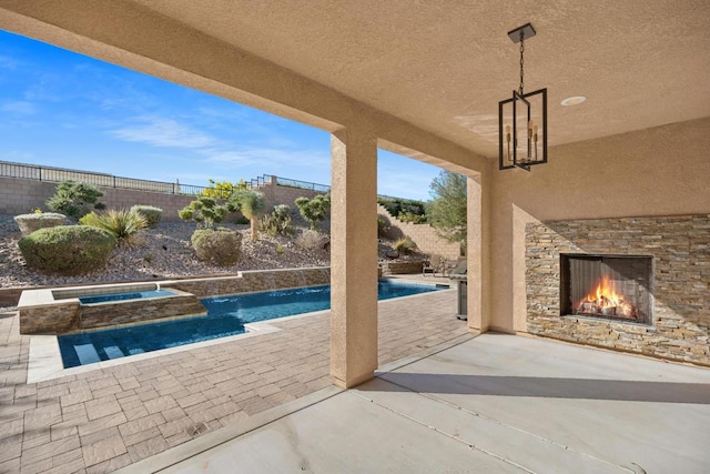 view of swimming pool featuring an in ground hot tub, an outdoor stone fireplace, and a patio area