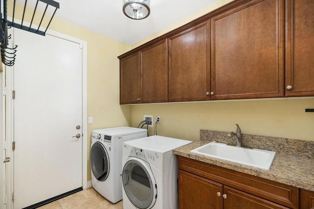 clothes washing area featuring separate washer and dryer, sink, light tile patterned floors, and cabinets