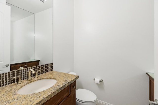 bathroom with vanity, toilet, and backsplash