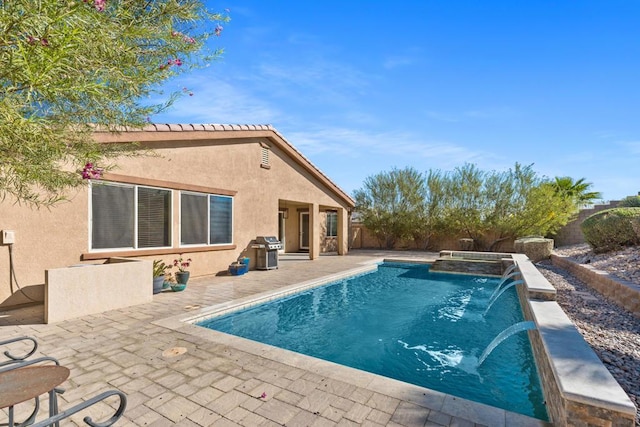 view of pool featuring area for grilling, pool water feature, a patio, and a hot tub