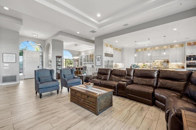 living room featuring a raised ceiling and light wood-type flooring