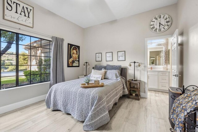 bedroom with ensuite bathroom and light hardwood / wood-style flooring