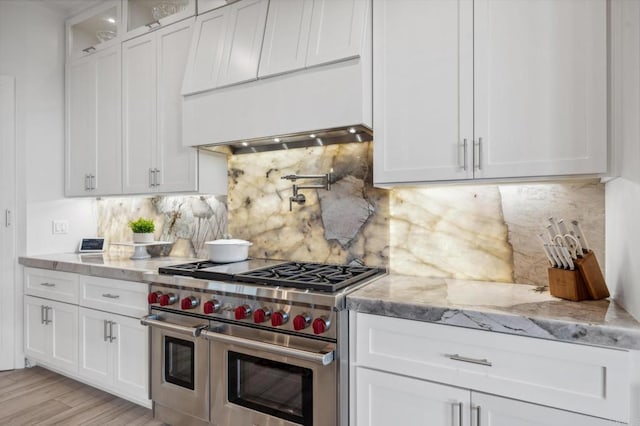 kitchen with tasteful backsplash, white cabinetry, double oven range, and light wood-type flooring