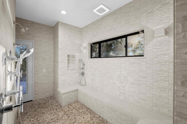 bathroom with tiled shower and tile walls