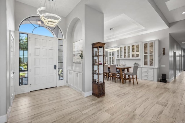 entryway with light hardwood / wood-style flooring, a high ceiling, and a chandelier