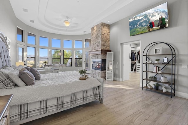 bedroom featuring ceiling fan, light hardwood / wood-style flooring, a towering ceiling, a walk in closet, and a closet