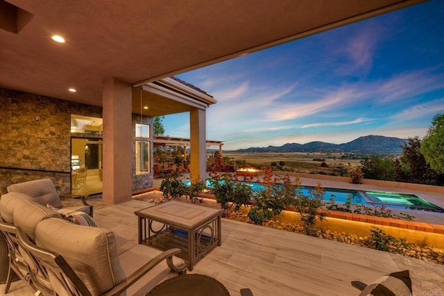 patio terrace at dusk with a mountain view and a pool with hot tub