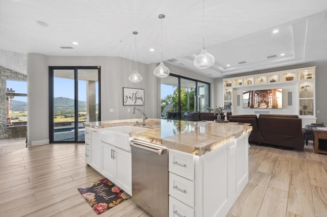 kitchen with white cabinets, a mountain view, an island with sink, and a healthy amount of sunlight