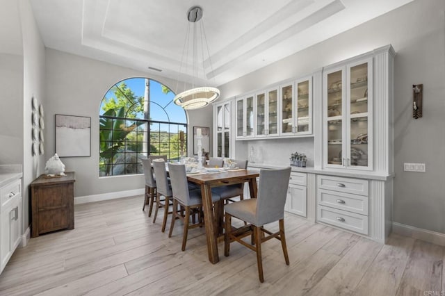 dining room with a tray ceiling and light hardwood / wood-style floors