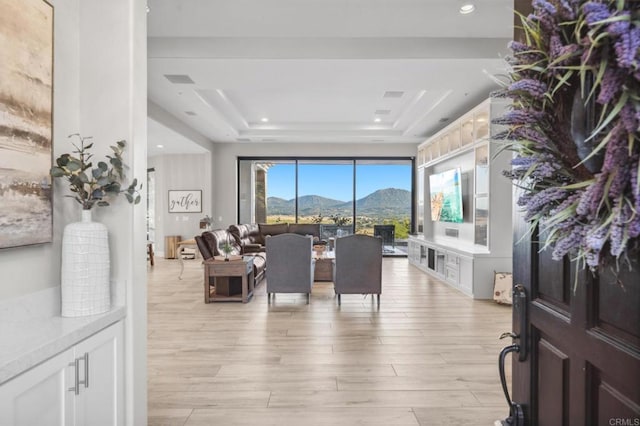 living room with a raised ceiling and light wood-type flooring