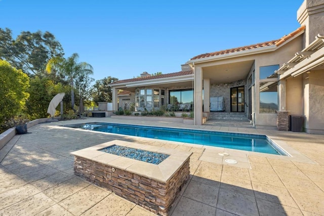 view of swimming pool with a patio, central AC, and an outdoor fire pit