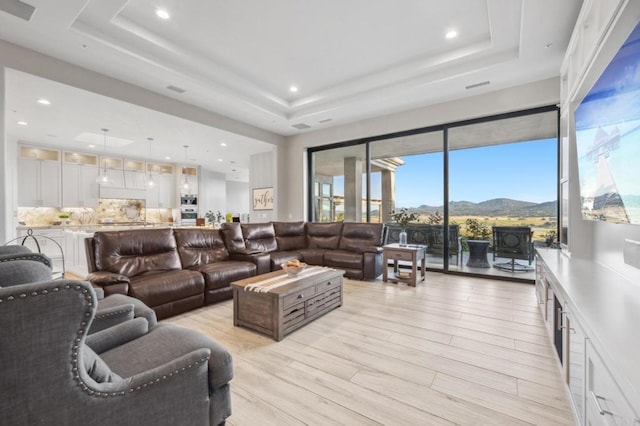 living room featuring a mountain view, light hardwood / wood-style flooring, and a raised ceiling