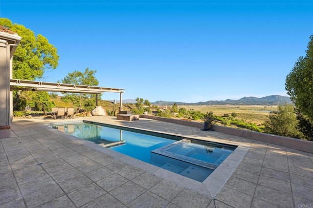 view of pool featuring a mountain view, a patio, and an in ground hot tub