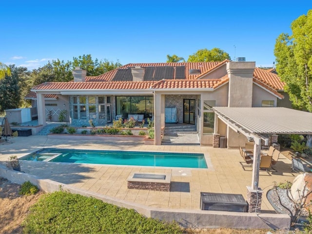 rear view of house featuring solar panels, a patio, a tiled roof, and a chimney