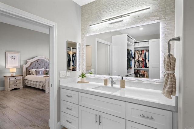 bathroom featuring a walk in closet, wood finished floors, and vanity