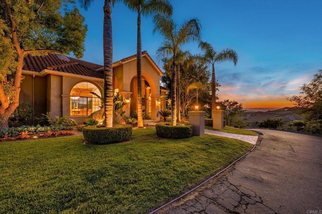 exterior space with a tiled roof, a yard, driveway, and stucco siding