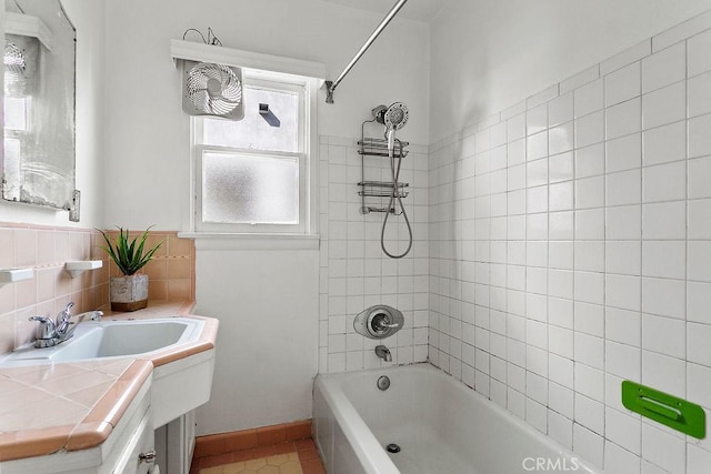 bathroom with tile patterned flooring, tiled shower / bath, and vanity