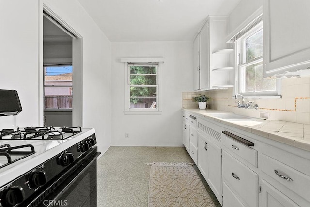 kitchen featuring tile countertops, range with gas stovetop, and white cabinets