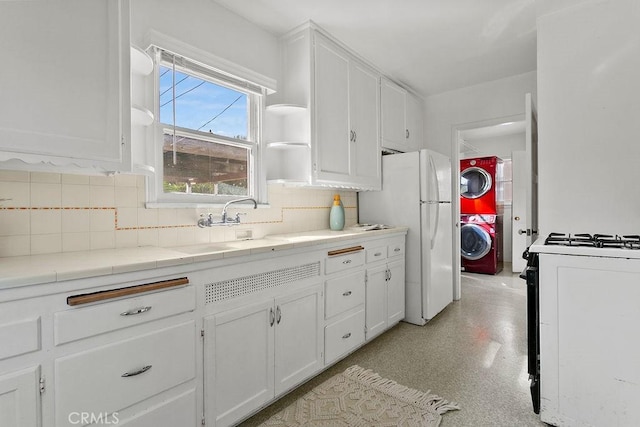 kitchen with white cabinetry, white refrigerator, decorative backsplash, gas range, and tile countertops