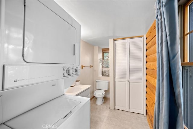 bathroom featuring vanity, stacked washer and dryer, and toilet