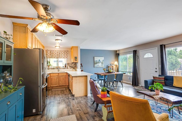 kitchen featuring stainless steel refrigerator, ceiling fan, dark wood-type flooring, a kitchen island, and backsplash