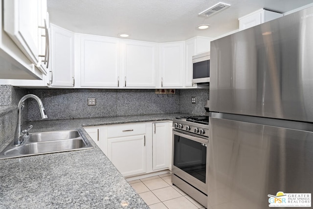 kitchen featuring white cabinetry, sink, backsplash, light tile patterned floors, and appliances with stainless steel finishes