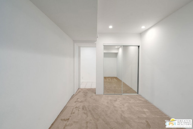 unfurnished bedroom with light carpet and a closet